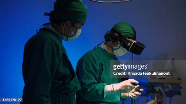 doctors in vr glasses performing surgery in hospital. - biomedical animation stock pictures, royalty-free photos & images