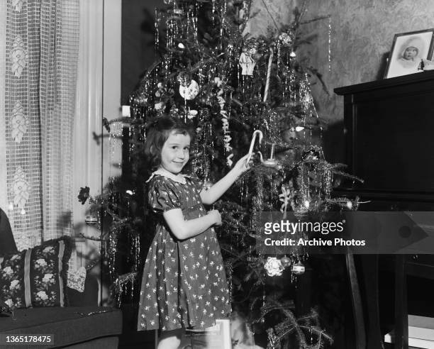 Young Marlene Ross helps to decorate a Christmas tree in Newton, Massachusetts, USA, December 1939.