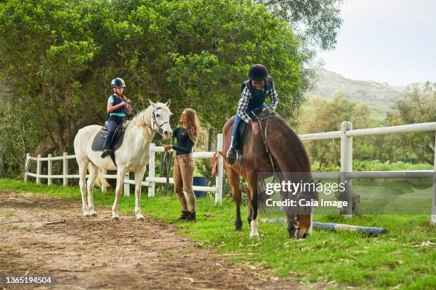 girls preparing for horseback riding lesson at rural paddock - black horse stockfoto's en -beelden