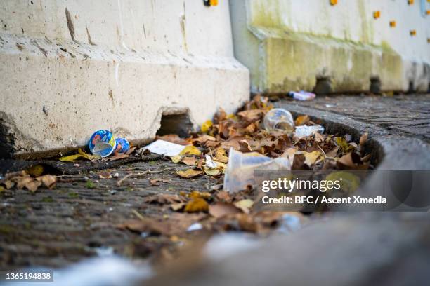 view of garbage littered on city street - leaflitter stock-fotos und bilder