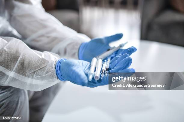 medical worker presenting variety of covid-19 vaccines - operating gown stock pictures, royalty-free photos & images