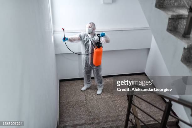 focused medical worker sanitizing stairs and hallway in apartment building - white suit stock pictures, royalty-free photos & images