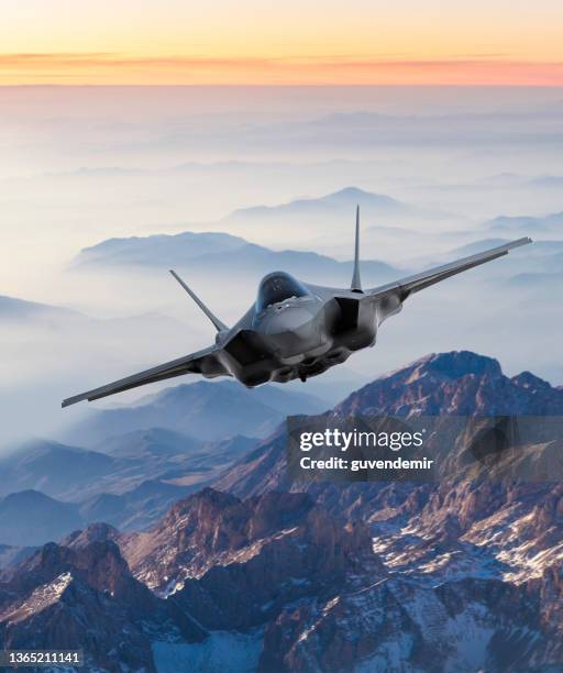 fighter jet flying over mountains at sunset - aviation stockfoto's en -beelden