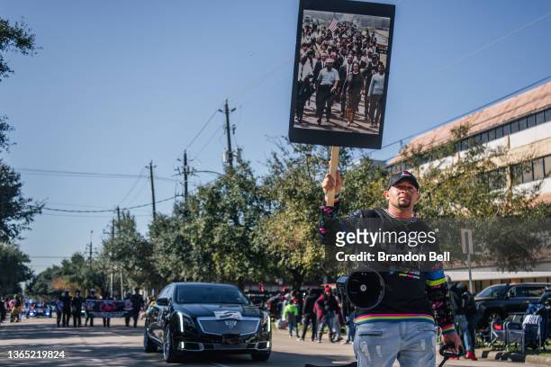 Person walks with a banner, of civil rights leaders marching, during the 28th Annual Martin Luther King Jr. Grande Parade on January 17, 2022 in...