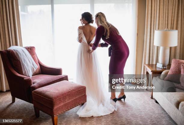 bride's maid helping bride prepare for wedding family on smartphone - bruidsmeisje stockfoto's en -beelden