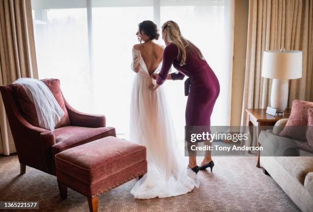 bride's maid helping bride prepare for wedding family on smartphone - bride getting dressed stock pictures, royalty-free photos & images