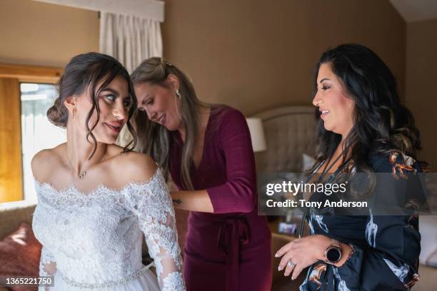 bridesmaids helping bride dress for wedding - bride getting dressed stock pictures, royalty-free photos & images