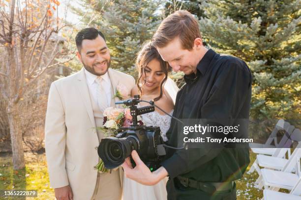 bride and groom working with camera operator at outdoor wedding - photographer 個照片及圖片檔
