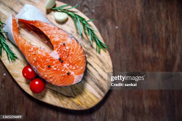 salmon. raw trout fish steak with ingredients, tomatoes rosemary and garlic on a wooden table - redfish stockfoto's en -beelden