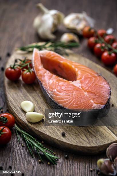 lachs. rohes forellenfischsteak mit zutaten, tomaten rosmarin und knoblauch auf einem holztisch - lachssteak stock-fotos und bilder