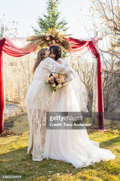 bride embracing mother in law at wedding ceremony - mother in law stock pictures, royalty-free photos & images
