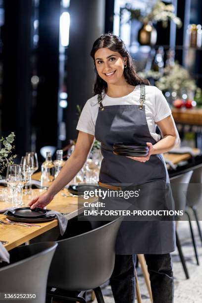 beautiful waitresses working in a restaurant and decorating a table for dinner - kellner oder kellnerin stock-fotos und bilder