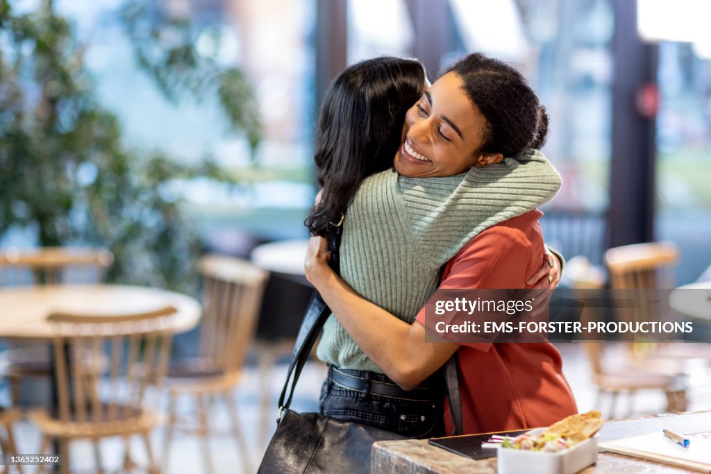 Two friends embrace each other lovingly at cafe