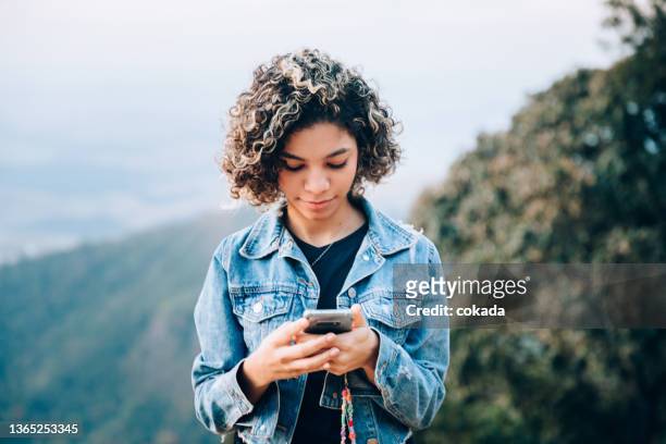 teenager using cell phone outdoors - juventude imagens e fotografias de stock