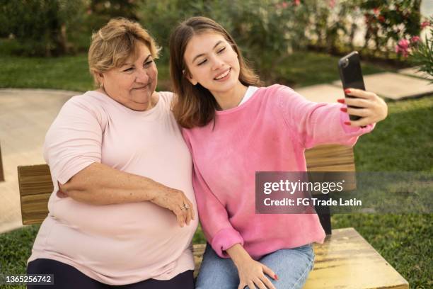 nonna e nipote che fanno una videochiamata su smartphone all'aperto - chubby granny foto e immagini stock