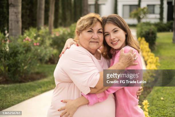 portrait of grandmother and granddaughter embracing outdoors - chubby granny stock pictures, royalty-free photos & images