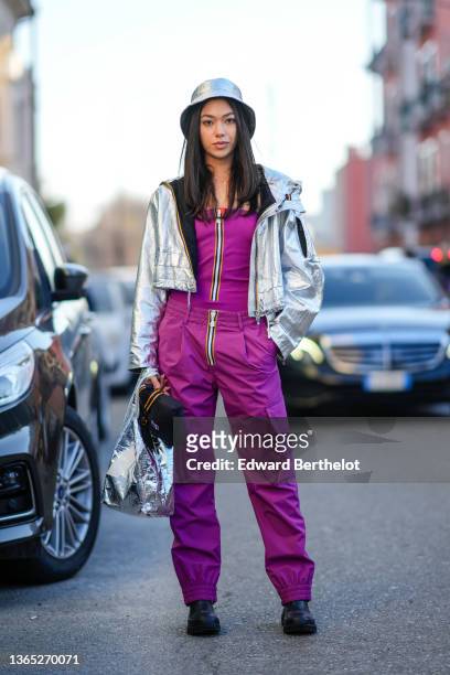 Stella Maya Epifani wears a K-Way full look, a silver shiny bob hat, a silver shiny cropped jacket, a purple top with front zipper, purple cargo...
