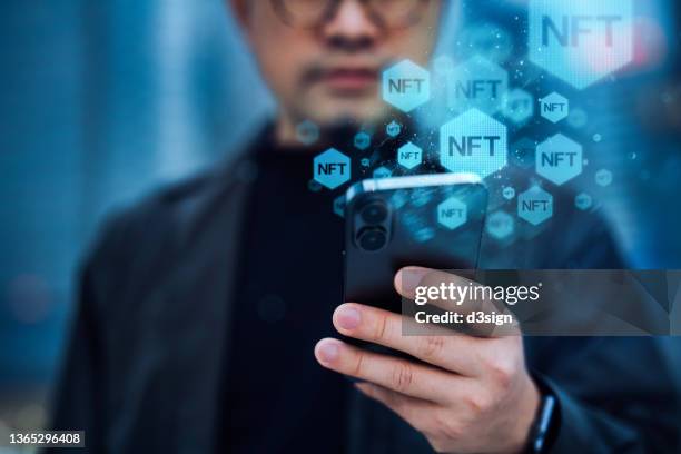 close up, mid-section of young asian businessman using smartphone in the city, working with blockchain technologies, investing or trading nft (non-fungible token) on cryptocurrency, digital asset, art work and digital ledger - virtual auction stock pictures, royalty-free photos & images