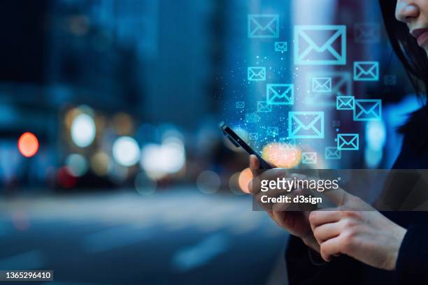 close up of young asian woman sending email with smartphone in the city, against illuminated city street lights in downtown district. information technology concept - sms icon photos et images de collection