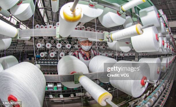 An employee works on the production line of polyester yarns at a textile factory on January 18, 2022 in Xinyu, Jiangxi Province of China.