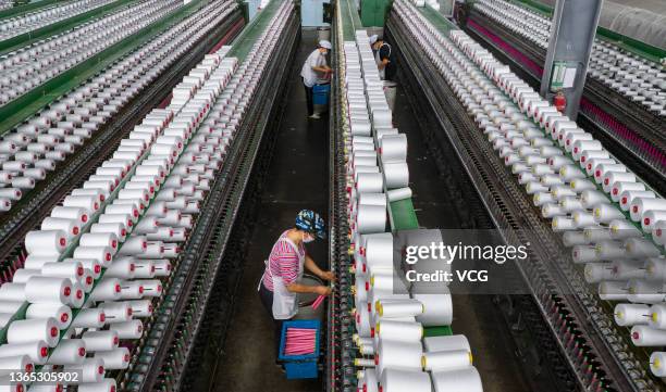 An employee works on the production line of polyester yarns at a textile factory on January 18, 2022 in Xinyu, Jiangxi Province of China.