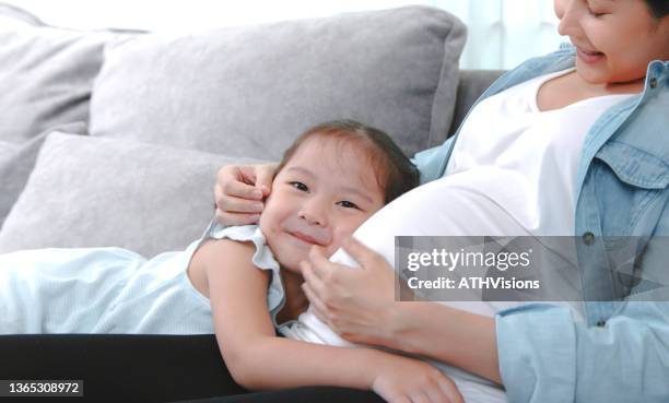 glückliches kleines kleinkind umarmt ihre schwangere mutter - kids belly stock-fotos und bilder
