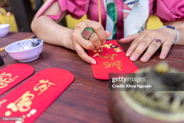 close-up mão de estudioso vietnamita escreve caligrafia no ano novo lunar. o festival de caligrafia é uma tradição popular durante o feriado do tet. - tet - fotografias e filmes do acervo