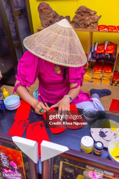 beautiful vietnamese scholar writes calligraphy at lunar new year. calligraphy festival is a popular tradition during tet holiday in vietnam - ao dai stockfoto's en -beelden