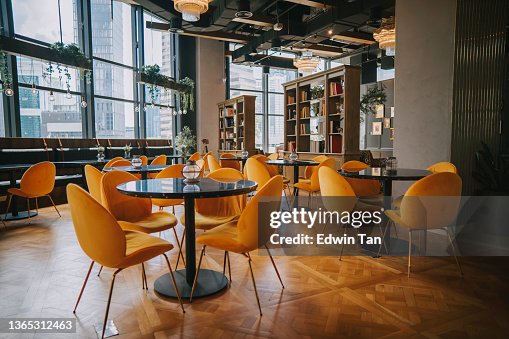 Modern Cafe restaurant interior with yellow chair against window with city view Modern Cafe restaurant interior with yellow chair against window with city view