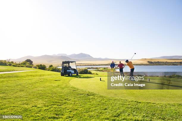 male golfer teeing off at sunny lakeside tee box - golf tee ストックフォトと画像