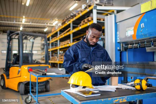 schwarzer männlicher ingenieur, der in der fabrik am digitalen tablet arbeitet - mechanic tablet stock-fotos und bilder