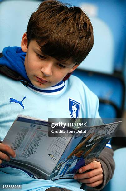 Boy reads his program during the FA Cup 3rd round match between Coventry City and Southampton at the Ricoh Arena on January 07, 2012 in Coventry,...