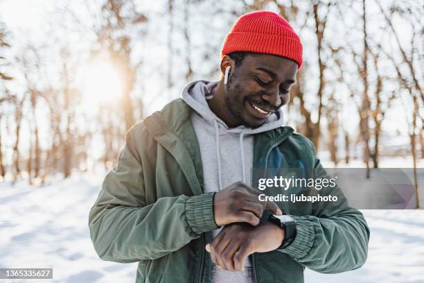 male runner uses app on smartwatch - winter testing imagens e fotografias de stock