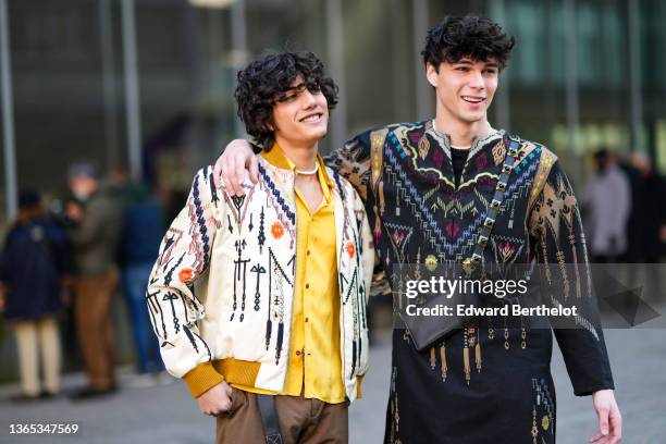 Guest wears a white pearls necklace, a black t-shirt, a black with gold / burgundy / gran / blue / yellow embroidered pattern long sleeves /...