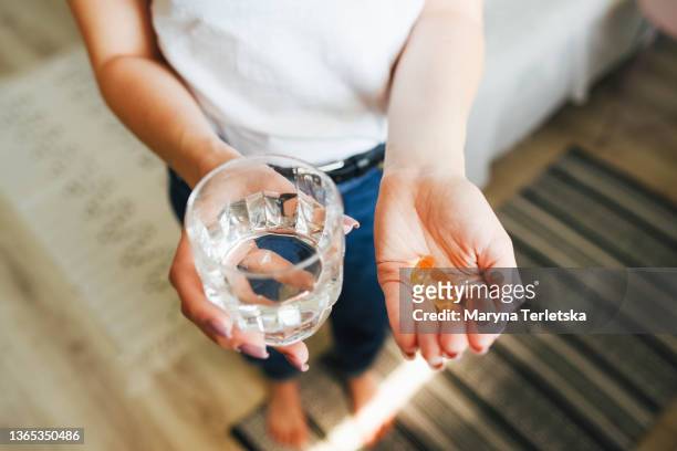 the girl holds vitamins and a glass of water in her hand. morning rituals. water. glass of water. water balance in the body. vitamins. vitamins and dietary supplements. - supplement stock pictures, royalty-free photos & images