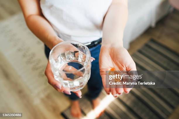 the girl holds vitamins and a glass of water in her hand. morning rituals. water. glass of water. water balance in the body. vitamins. vitamins and dietary supplements. - 鎂 個照片及圖片檔