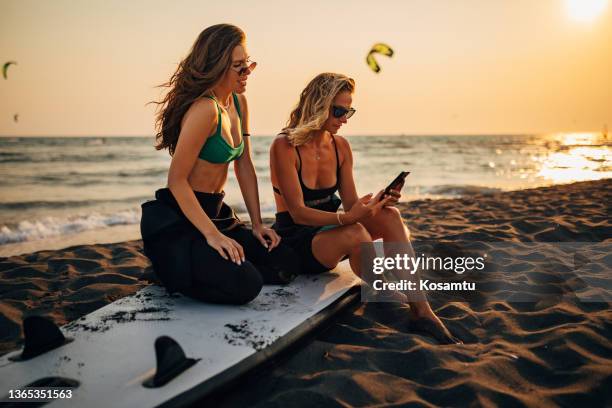 after surfing, best friends sat down to relax on the beach and take a few photos while the golden hour was still going on. - sattel bildbanksfoton och bilder