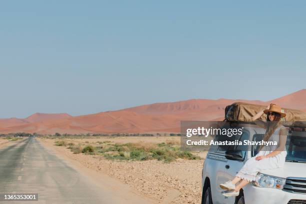 female traveler in dress and hat exploring namibia by camper truck - sossusvlei stock pictures, royalty-free photos & images