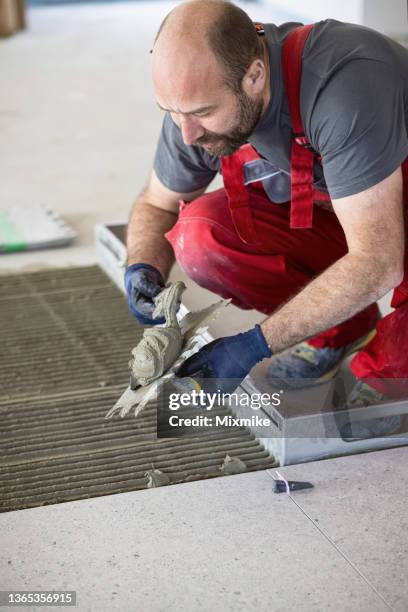 builder preparing and spreading tile adhesive on the floor - tile adhesive stock pictures, royalty-free photos & images