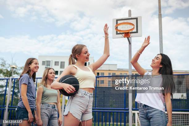 two girls does high five during a basketball game - women's basketball stockfoto's en -beelden