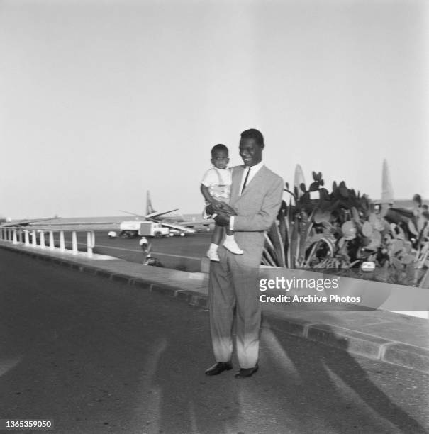 American singer, actor and jazz pianist Nat King Cole arrives at Nice Airport in France with his son Kelly, 5th August 1960.