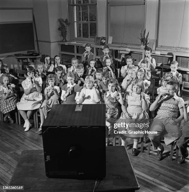 Group of schoolchildren watching a television set during a music lesson at school, for educational purposes, USA, 1950.