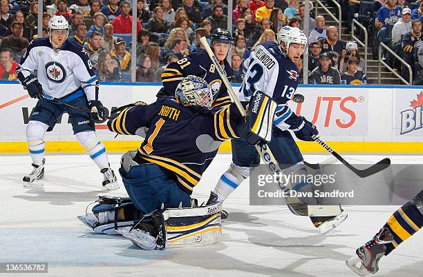 Jhonas Enroth of the Buffalo Sabres makes a blocker save as Kyle Wellwood and Nik Antropov, both of the Winnipeg Jets, look on as well as Brayden...