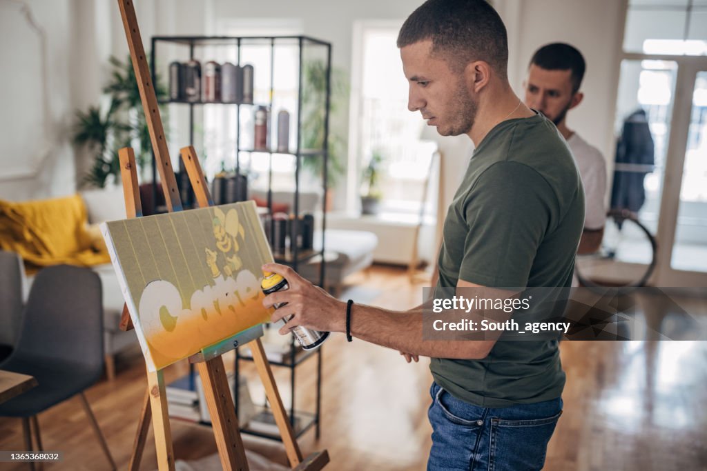 Artistas gemelos masculinos pintura en aerosol