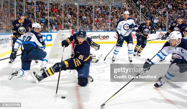 Brayden McNabb of the Buffalo Sabres stick handles the puck from his knees as Andrew Ladd of the Winnipeg Jets defends while Tyler Myers of the...