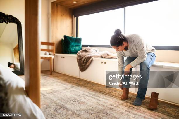 woman putting on a shoe at home - booties stock pictures, royalty-free photos & images