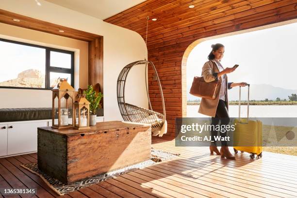 young woman with a luggage using her phone at her holiday home - vakantiehuis stockfoto's en -beelden