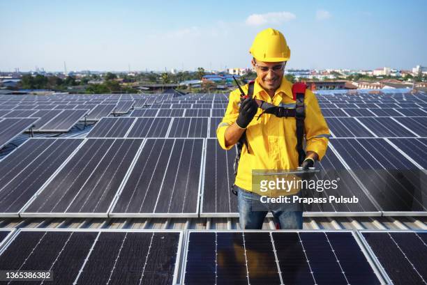 Engineers holding tablet standing at solar panels roof