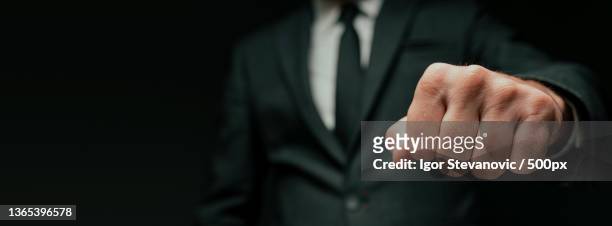 businessman greeting with fist bump,midsection of businessman gesturing while standing against black background,serbia - leadership fist ストックフォトと画像