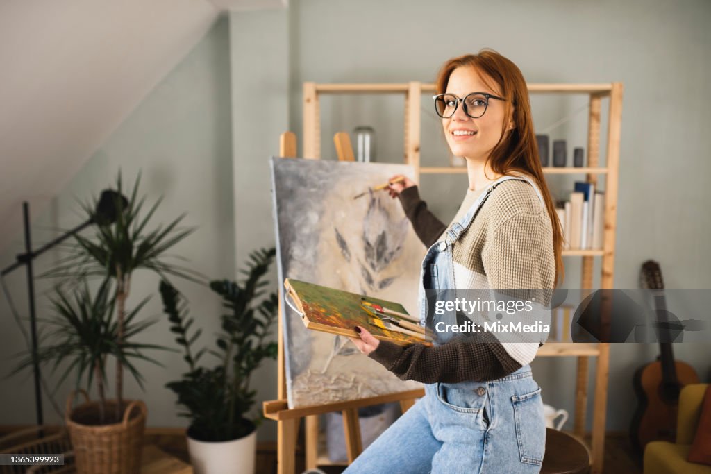 Porträt einer glücklichen jungen Frau, die gerne zu Hause malt